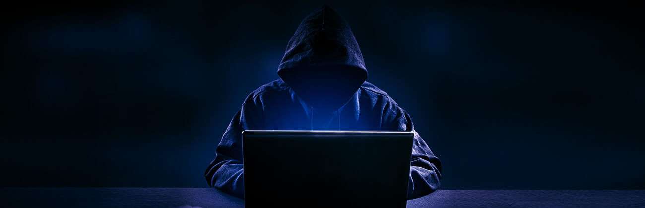 Social media impersonation hacker lurking on a laptop in the dark creates fake profiles for identity theft.