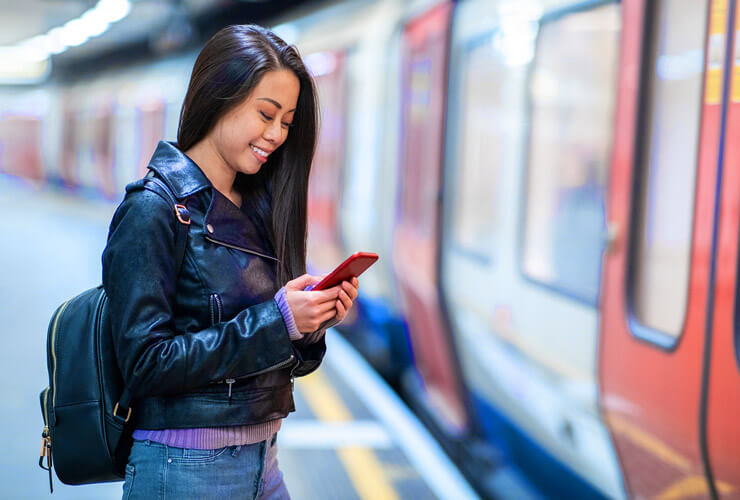 Asian woman in metro station using mobile device