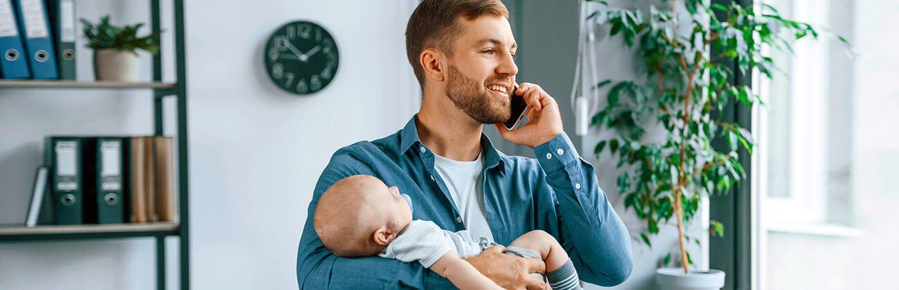 Dad talks on mobile phone while holding baby