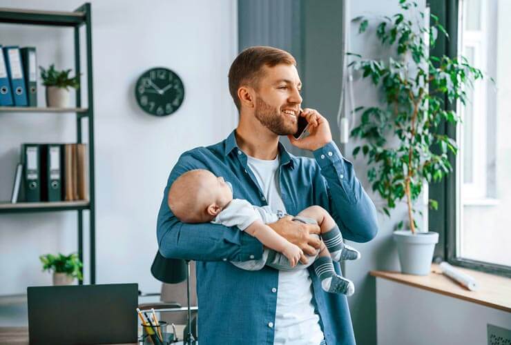 Dad talks on mobile phone while holding baby