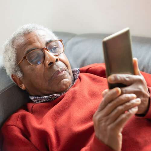 Man relaxing on sofa looks at cell phone to track his data usage