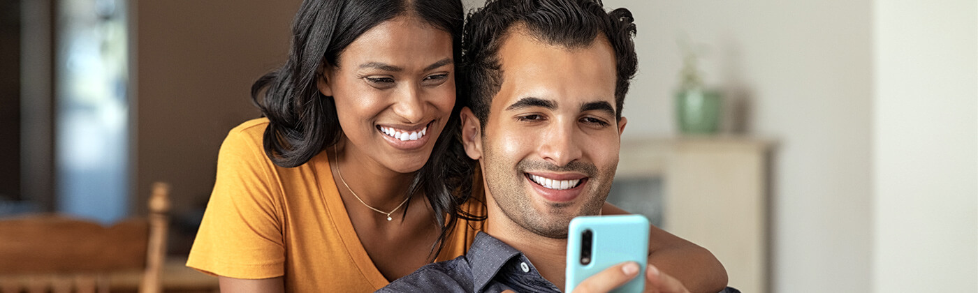 South Asian couple smile as they view their upgraded cell phone
