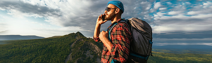 Man uses mobile phone while hiking in wilderness mountains