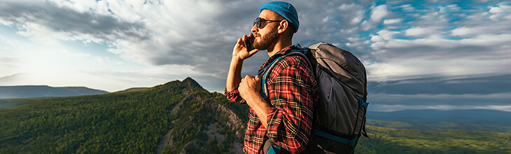Man uses mobile phone while hiking in wilderness mountains