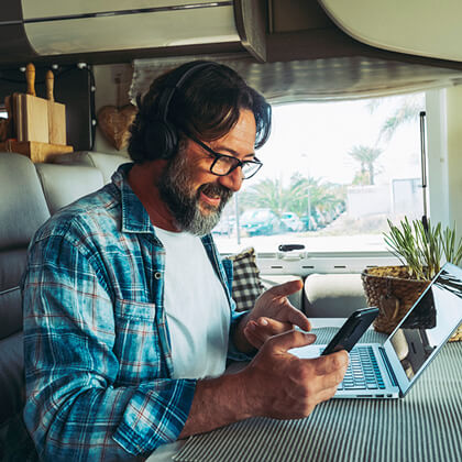 Traveler in RV on mobile phone and laptop