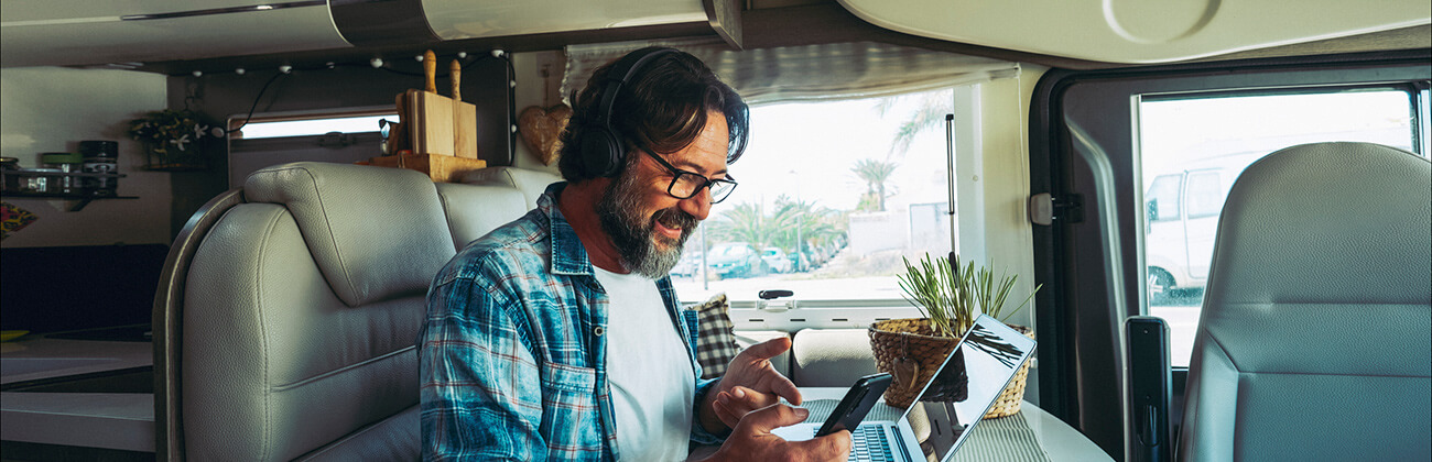 Traveler in RV on mobile phone and laptop