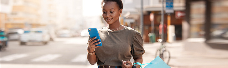 Posh dark-skinned woman shopping smiles at her new upgraded mobile phone