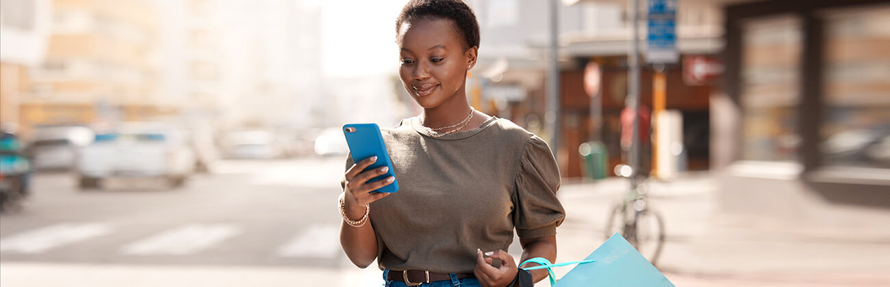 Posh dark-skinned woman shopping smiles at her new upgraded mobile phone