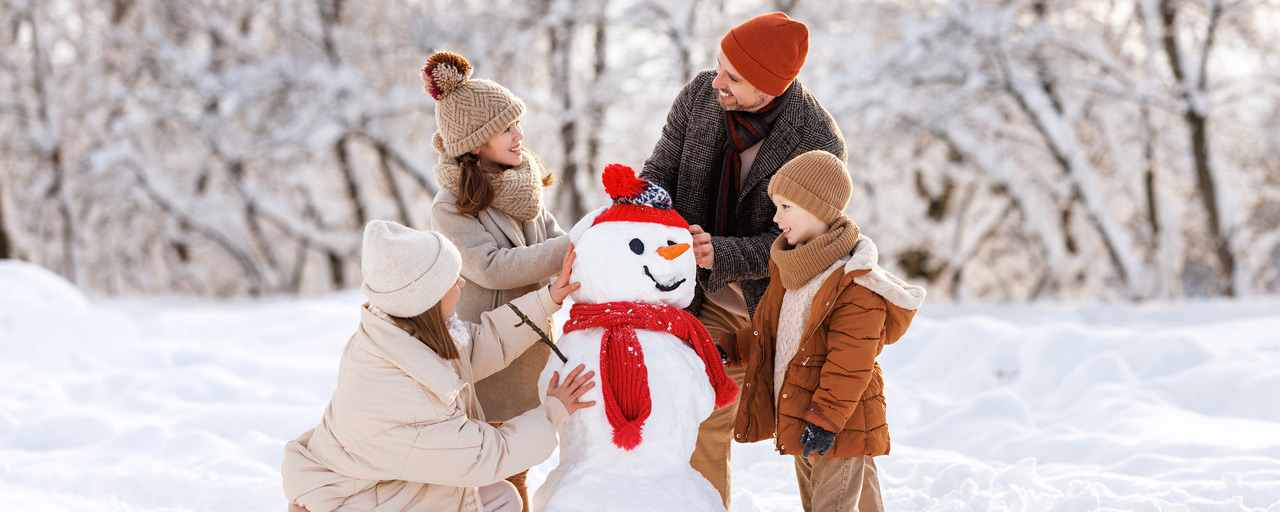 Family builds a snowman together in wintertime