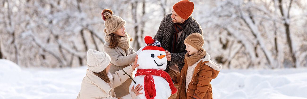 Family builds a snowman together in wintertime