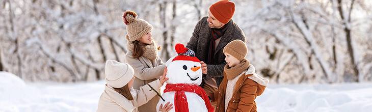 Family builds a snowman together in wintertime