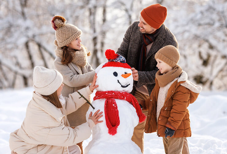 Family builds a snowman together in wintertime