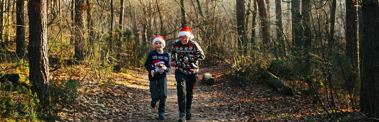 Holiday activity guide - two boys in Santa hats hike in the woods