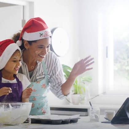 Mom and daughter in holiday hats on a virtual call
