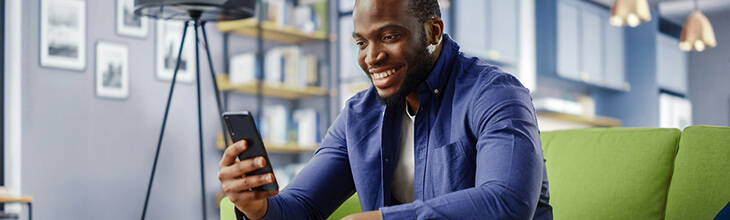 man sitting on a couch scrolling his phone