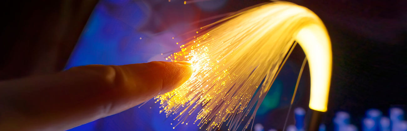 Glowing fiber optic strands being bundled for Fiber to the Home (FTTH)
