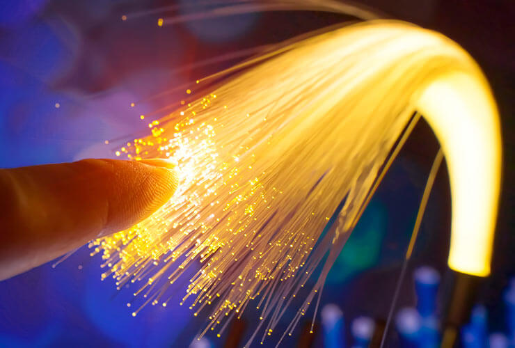 Glowing fiber optic strands being bundled for Fiber to the Home (FTTH)