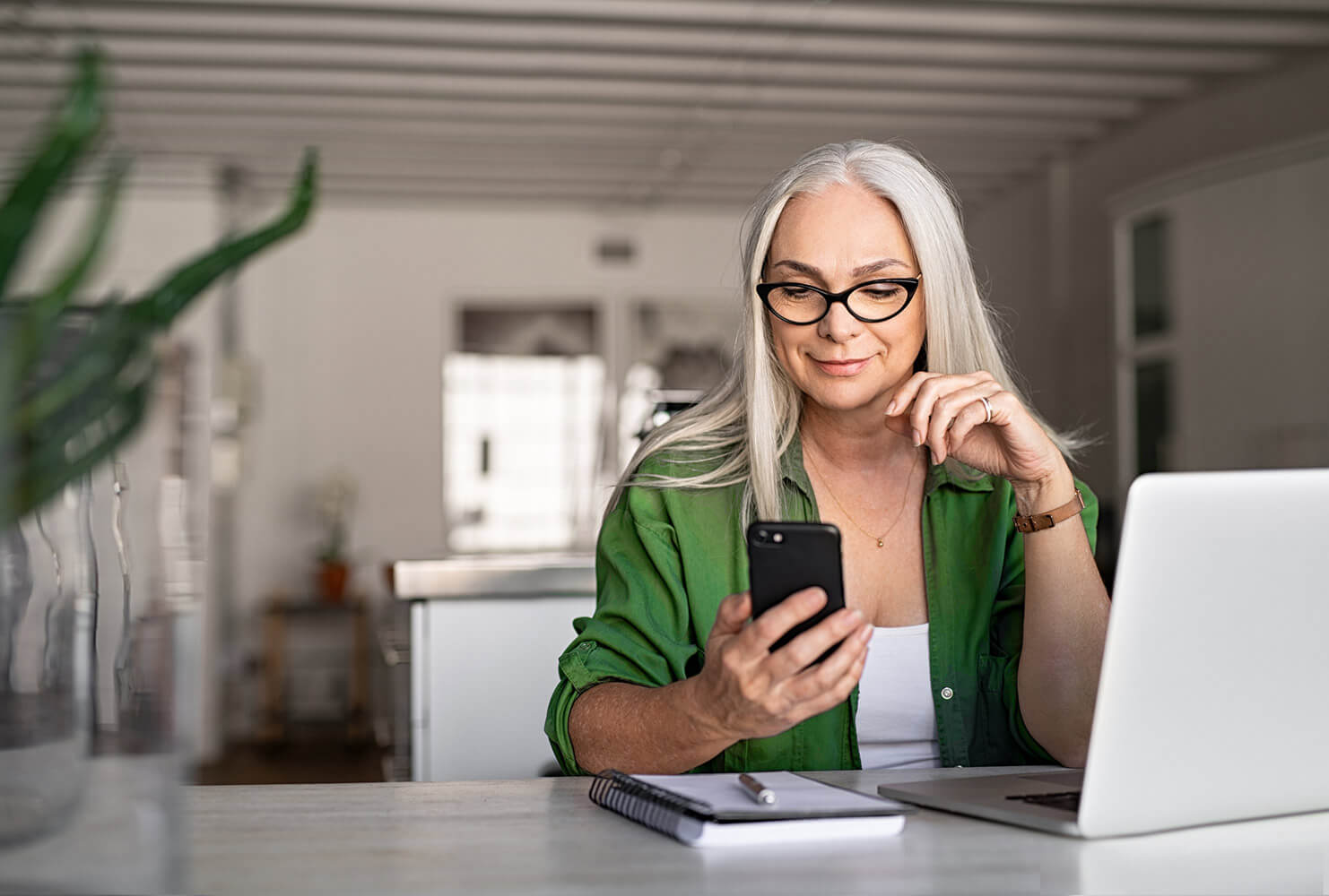 Woman at desk works from home with multiple devices.