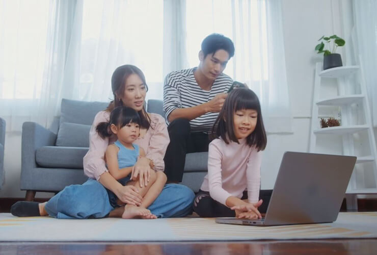 Young Asian family around laptop compares Astound vs Verizon 5G Home