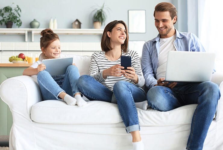 Family on couch each on their own device