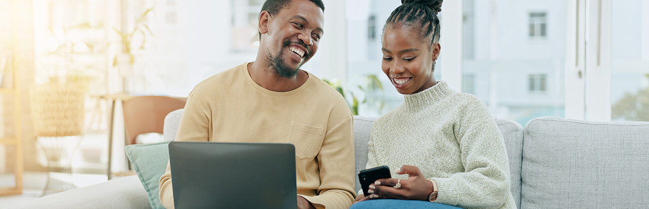 Father on a laptop smiling at daughter who is on cellphone