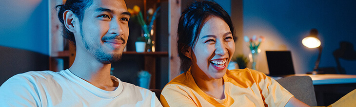 Smiling couple on sofa watching TV