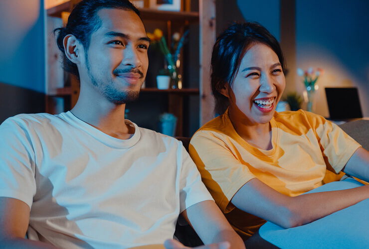 Smiling couple on sofa watching TV