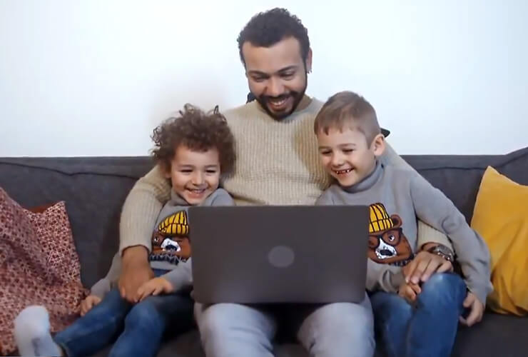 man and his two sons enjoy streaming tv on laptop