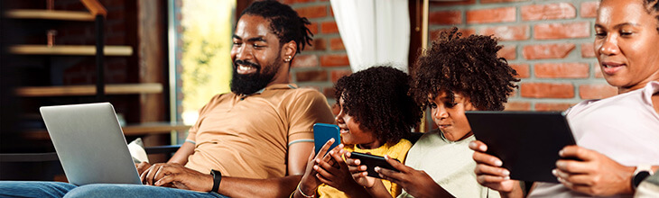 Family together on sofa each using their own devices