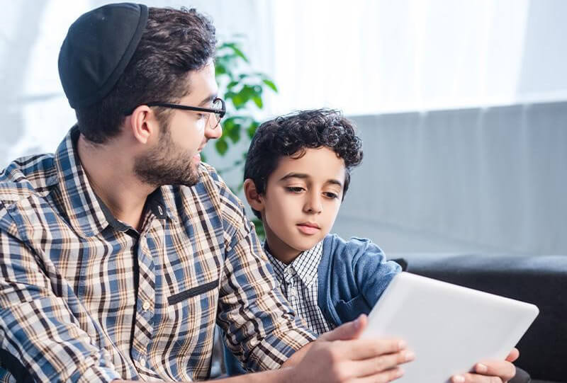 Dad and son with a tablet learn about Jewish heritage