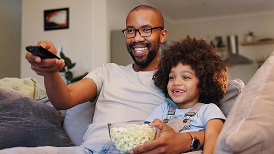 Dad and kid watch shows on tv together