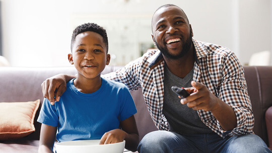 Dad and son watching favorite shows together on Father's Day