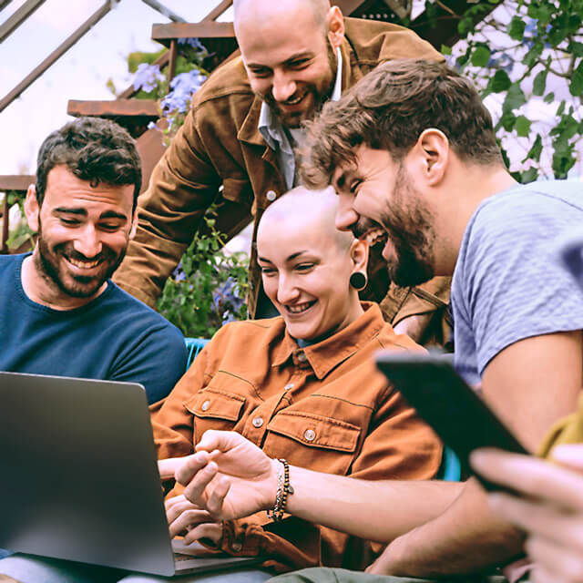 a group of friends gathers around laptop and tablet outside