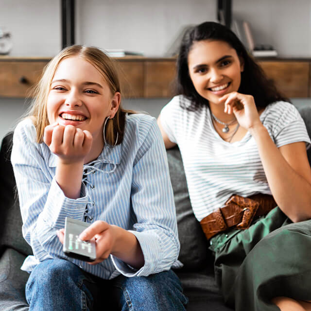 two women laugh while watching movies
