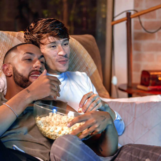 A couple eating popcorn watches TV