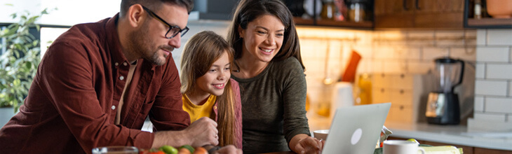 family uses a laptop in the kitchen - compare eero and Google WiFi systems based on your household needs.